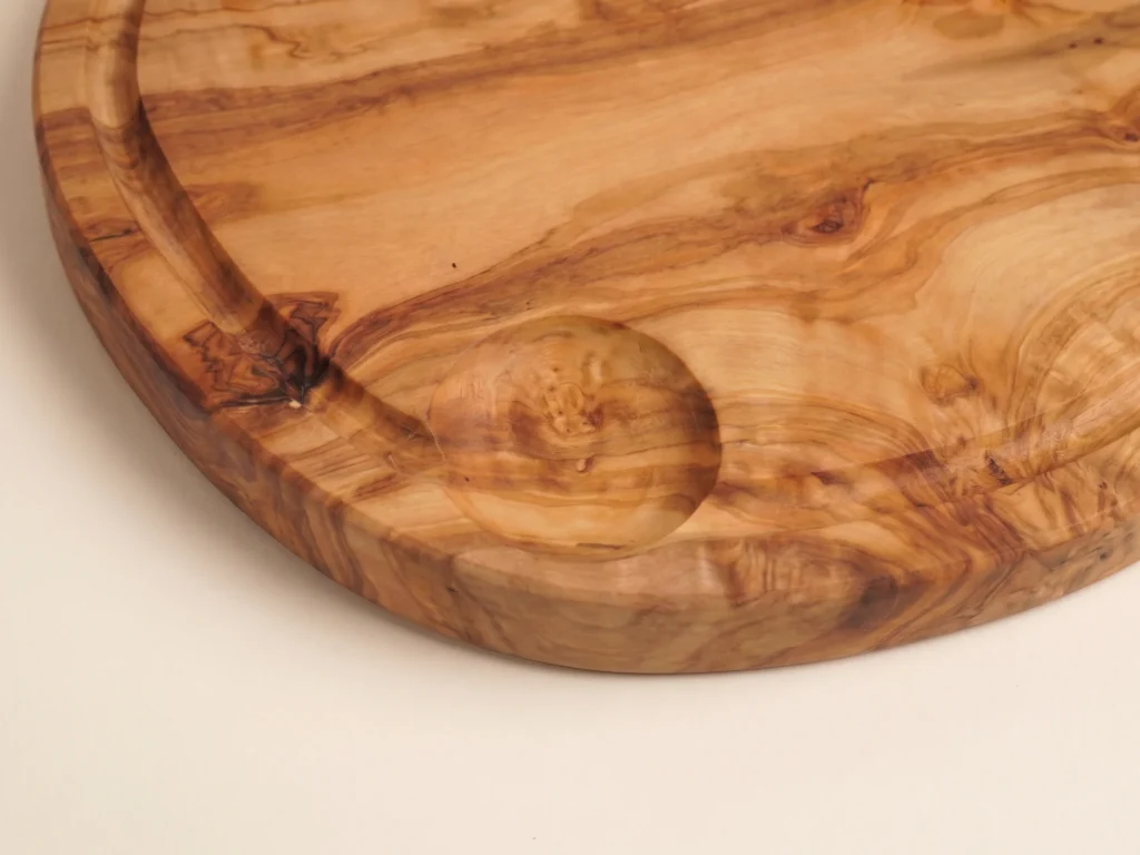 Close detail of the carved circular recess and groove in an olive wood board