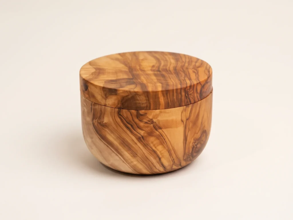 Olive wood salt keeper seen from a three-quarter angle showing cylindrical body and flush magnetic lid