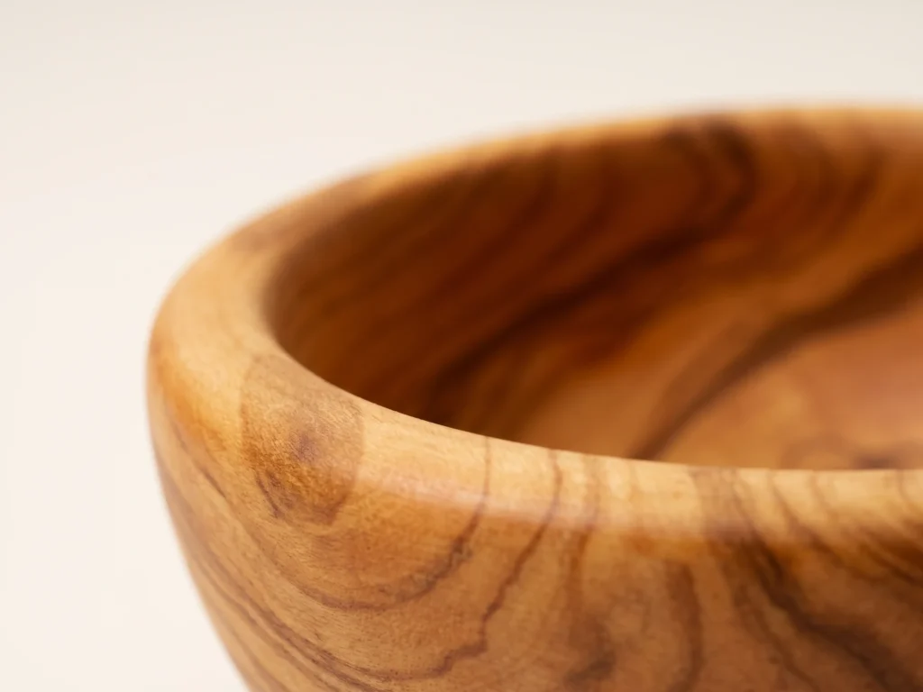Macro close-up of smooth rounded rim and dense olive wood grain on round bowl TR-1