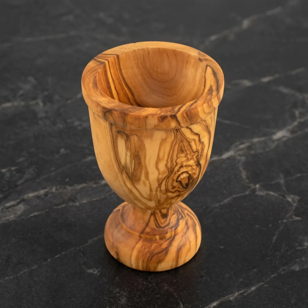 Handcrafted olive wood egg cup TR-22 on polished black Nero Marquina marble with delicate pedestal base