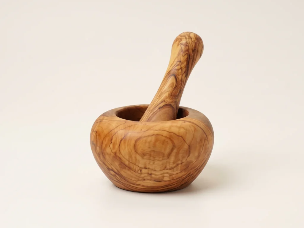 Low-profile side view of smooth round olive wood mortar with pestle standing inside