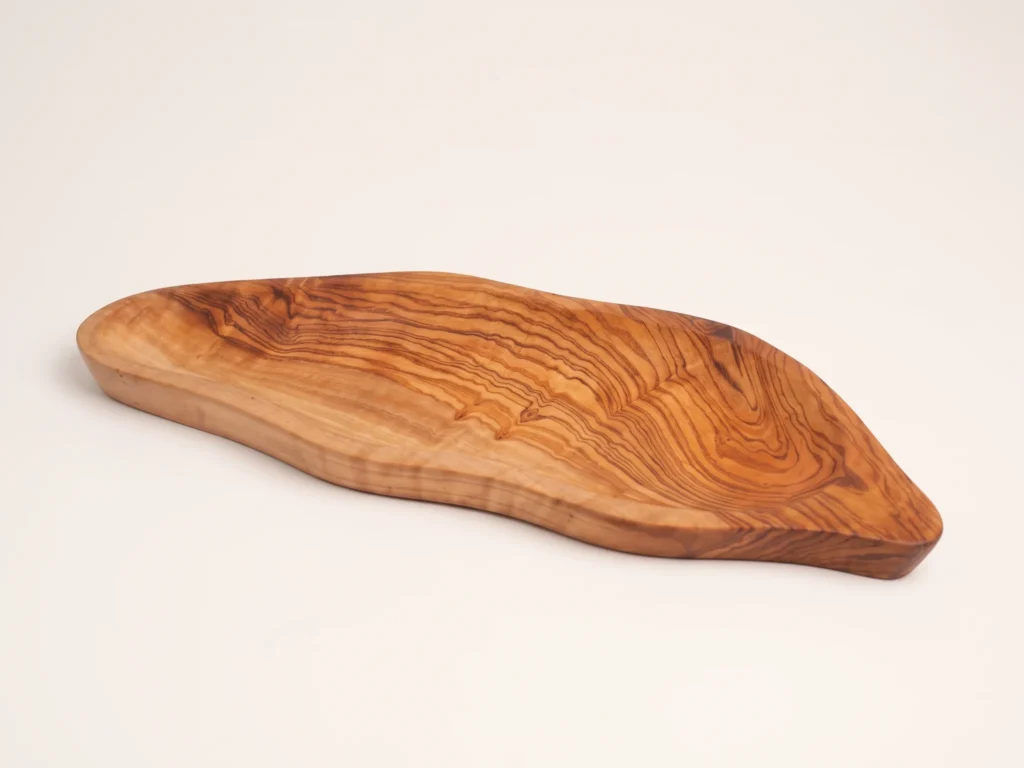 Three-quarter catalog angle of olive wood leaf plate BL-13 on warm ivory studio background