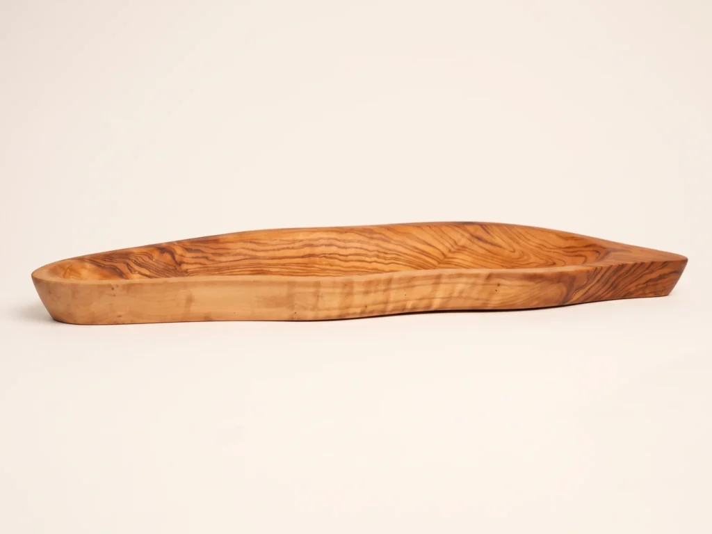 Low angle side profile of olive wood leaf plate BL-13 highlighting rim elevation and flat stable base