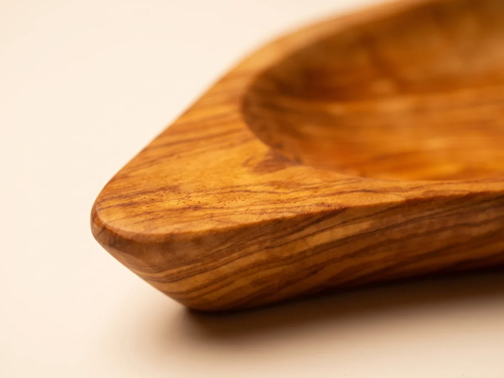 Extreme close-up macro of carved stem tip and undulating natural rim on olive wood leaf plate BL-13