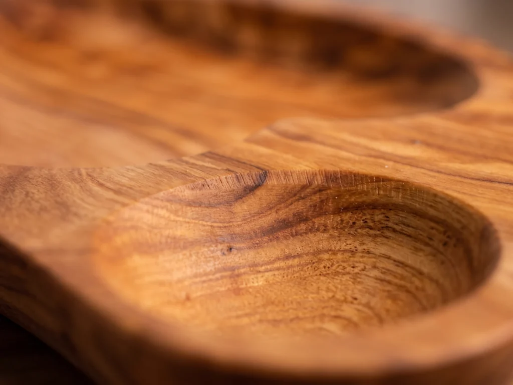 Extreme close-up macro view of the sculpted divider bridge and amber olive wood grain on dish BL-15