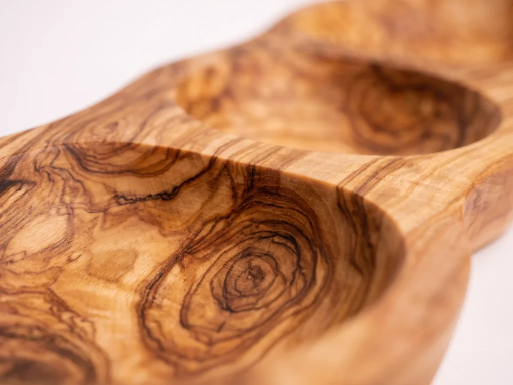 Macro close-up shot of the sculpted divider bridge and dramatic olive wood grain between compartments on platter BL-24