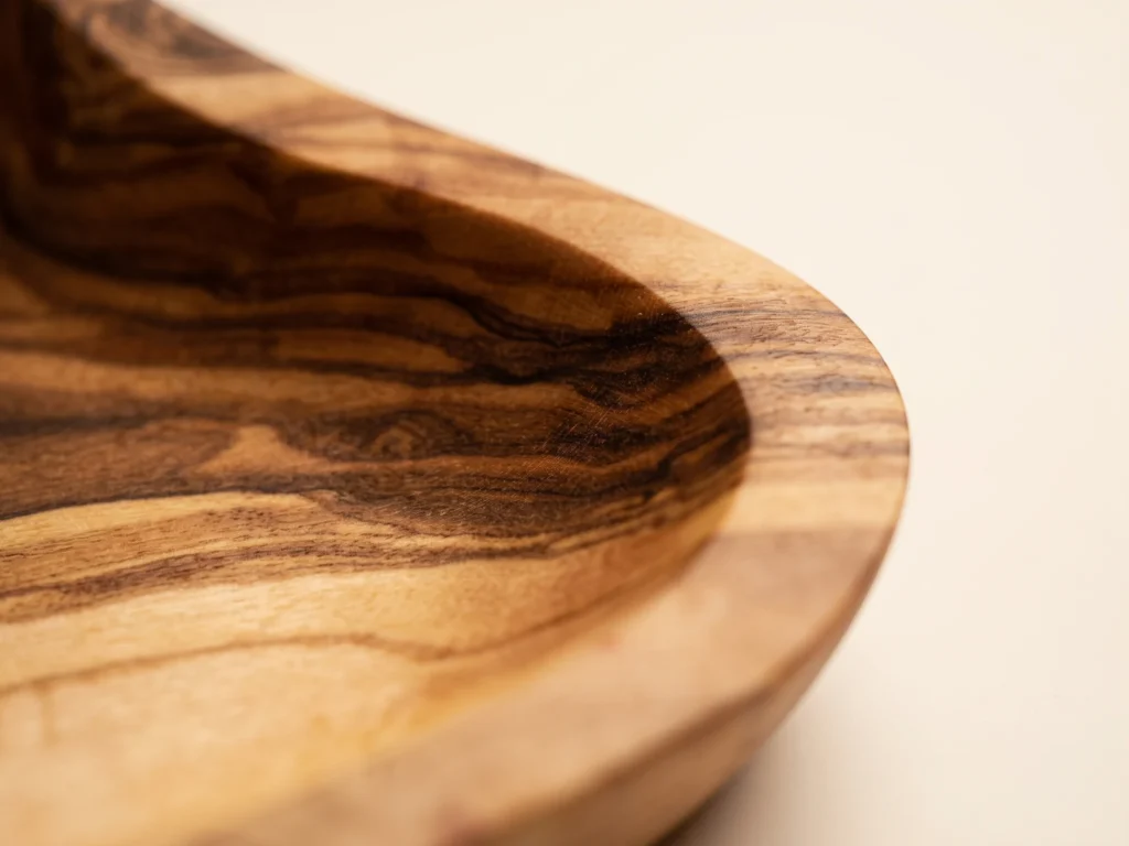 Extreme close-up macro view of olive wood heart dish BL-8 showing dense wood grain and satin oiled finish