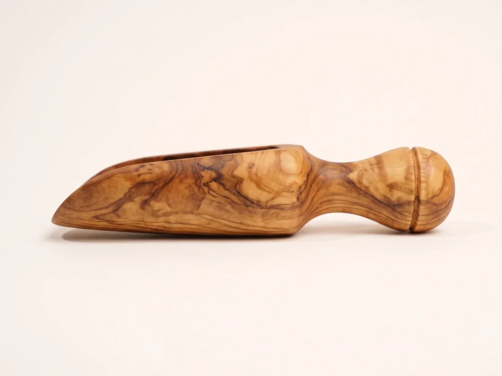 Olive wood spice scoop TR-23 low profile side silhouette showing flat resting base, curved chute, and turned end knob