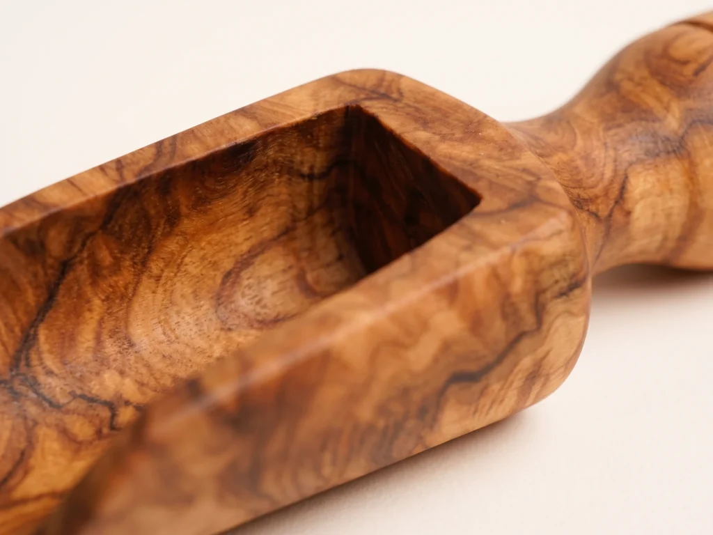 Macro close-up of olive wood spice scoop TR-23 trough transition, rear bulkhead, and turned handle neck with dense grain