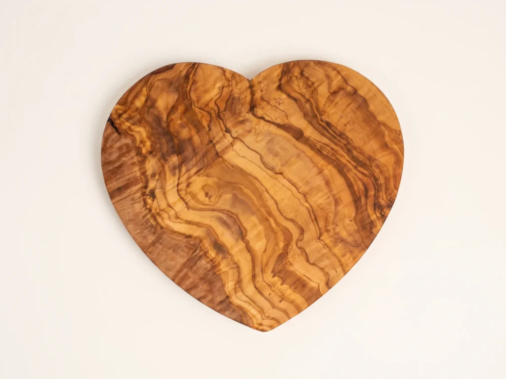 Heart-shaped olive wood cutting board overhead 90-degree technical flat-lay view