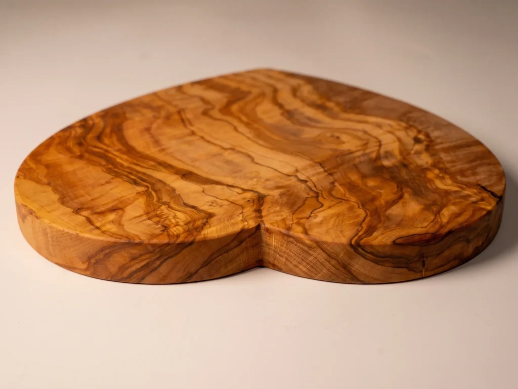Heart-shaped olive wood cutting board low-profile grazing edge view showing 2 cm thickness
