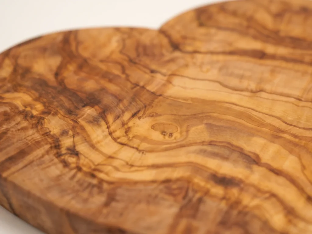 Heart-shaped olive wood cutting board macro detail of grain and heart curve