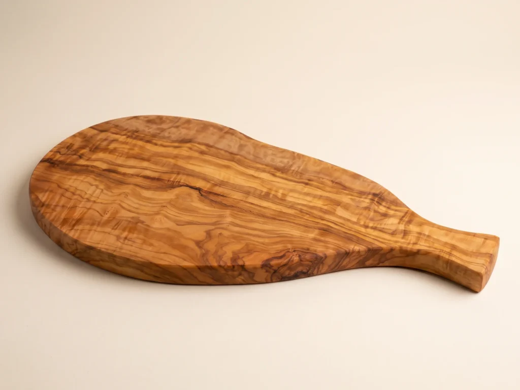Natural shaped olive wood cutting board with handle low three-quarter view