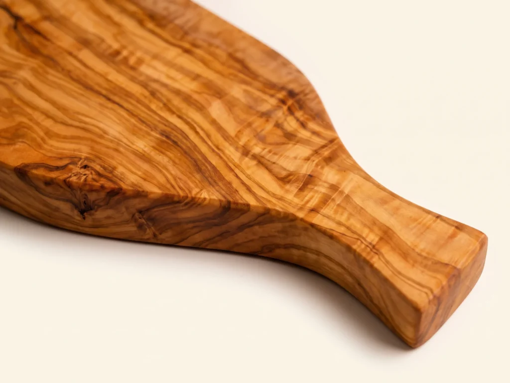 Natural shaped olive wood cutting board with handle macro detail of carved handle and grain