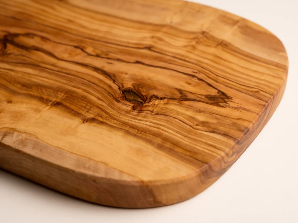 Natural shaped olive wood cutting board macro detail of wood grain and central knot