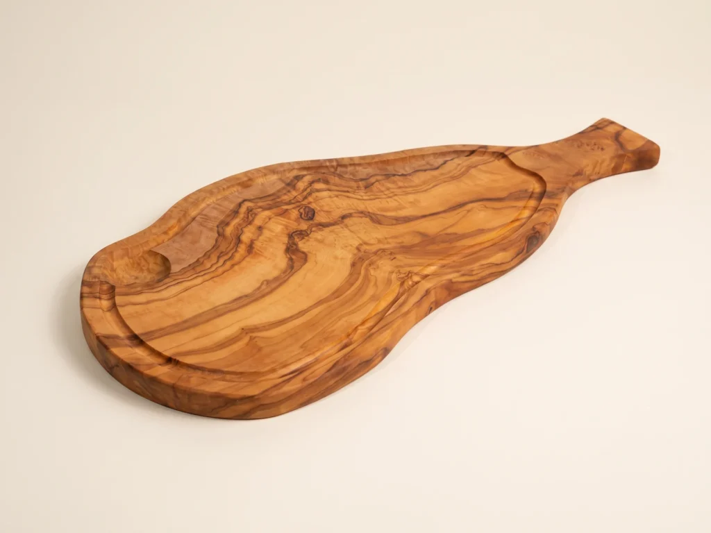 Natural shaped olive wood cutting board with juice groove and handle low-profile grazing edge view