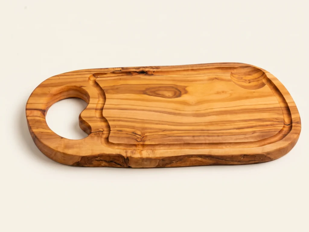 Natural shaped olive wood cutting board with juice groove and hole low three-quarter view