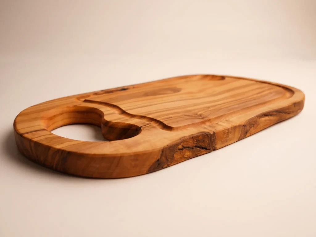 Natural shaped olive wood cutting board with juice groove and hole low-profile grazing edge view