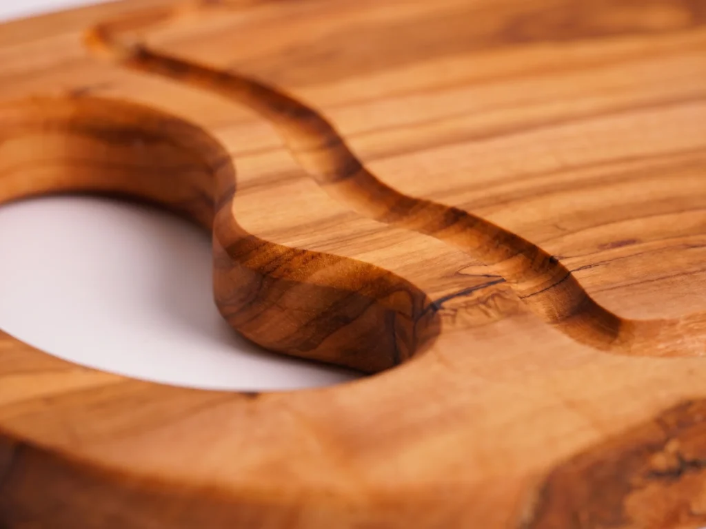 Natural shaped olive wood cutting board with juice groove and hole macro detail of handle hole and groove