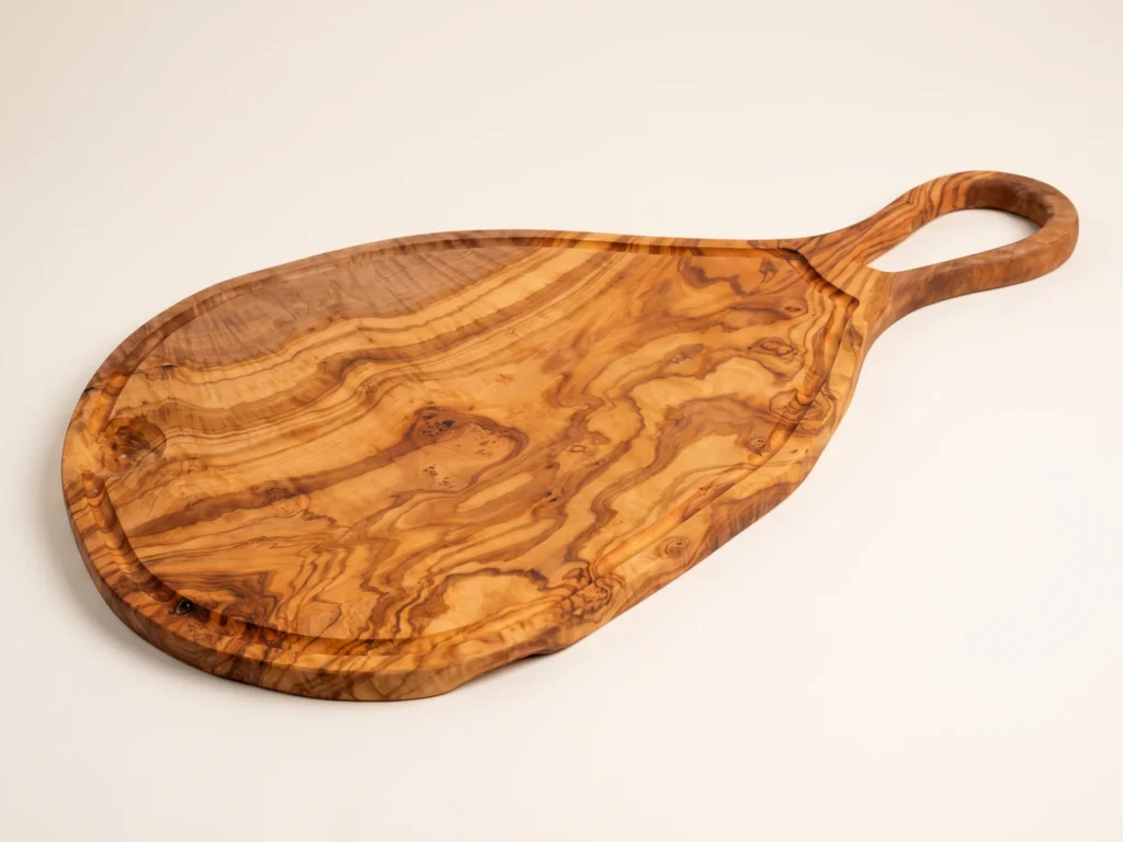 Large natural shaped olive wood cutting board with juice groove and hole low three-quarter view