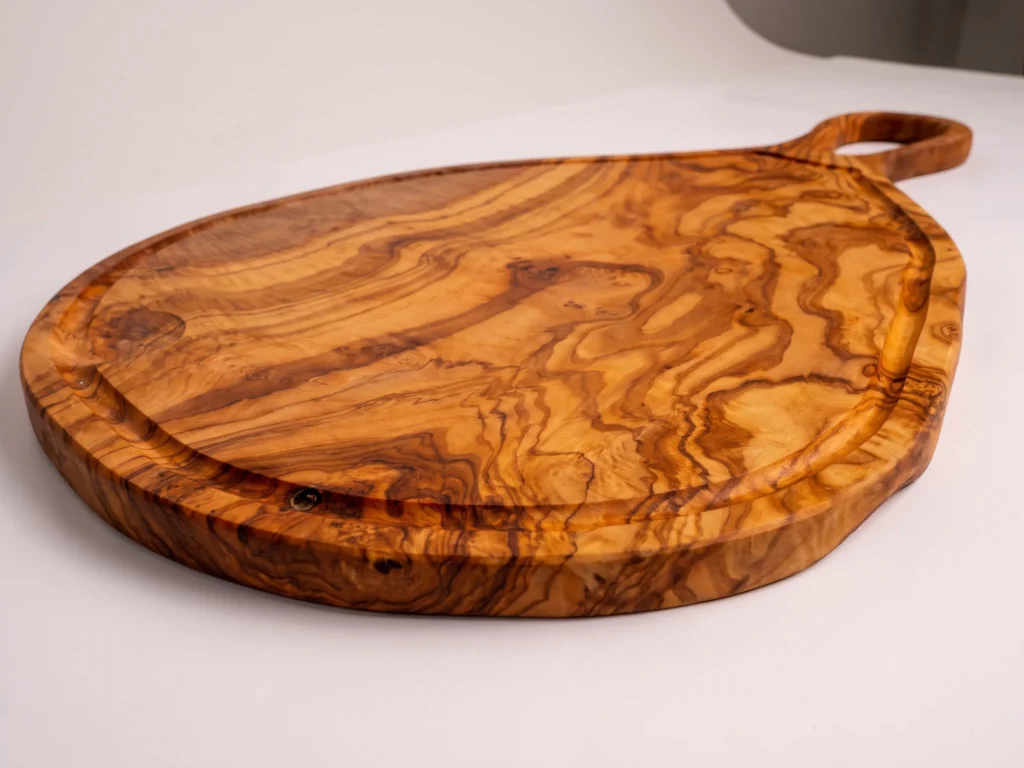 Large natural shaped olive wood cutting board with juice groove and hole low-profile grazing edge view