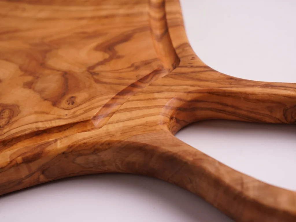 Large natural shaped olive wood cutting board with juice groove and hole macro detail of loop handle and groove