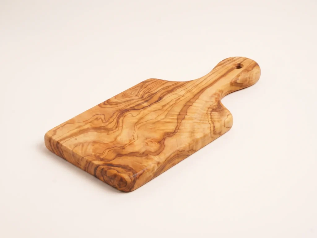 Olive wood persil board with sculpted handle low three-quarter perspective view