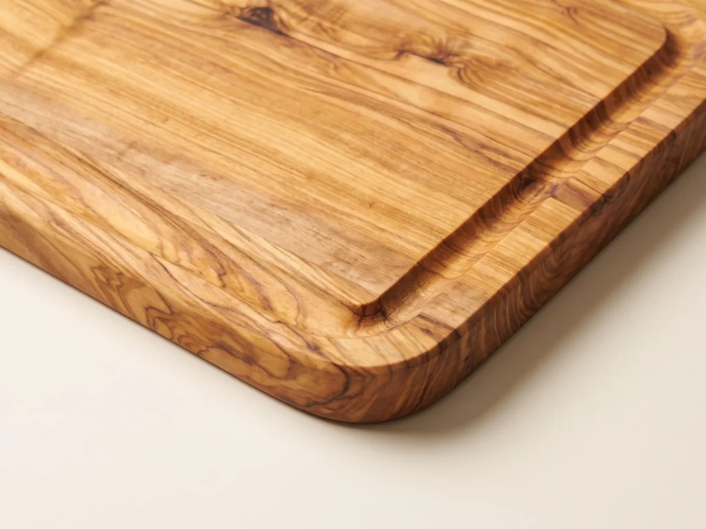 Rectangular edge-glued olive wood cutting board macro detail of corner and juice groove