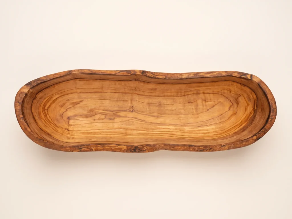 Top-down overhead view of rustic olive wood bread basket BL-2 showing boat-shaped basin and live-edge bark rim