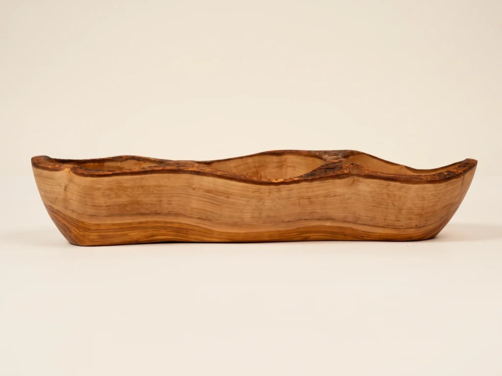 Side elevation view of rustic olive wood 3-compartment dish showing undulating silhouette and stable base