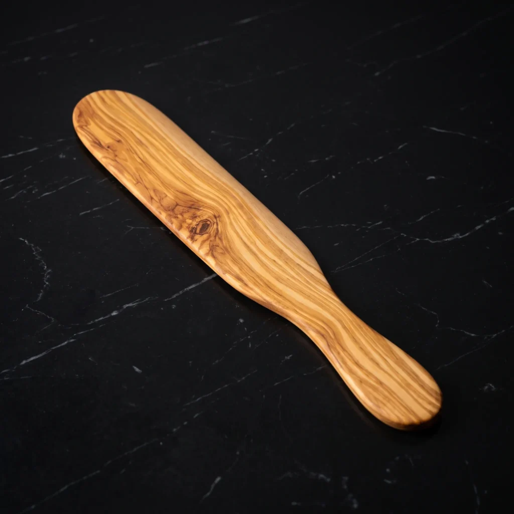 Olive wood perforated risotto spoon on a charcoal surface