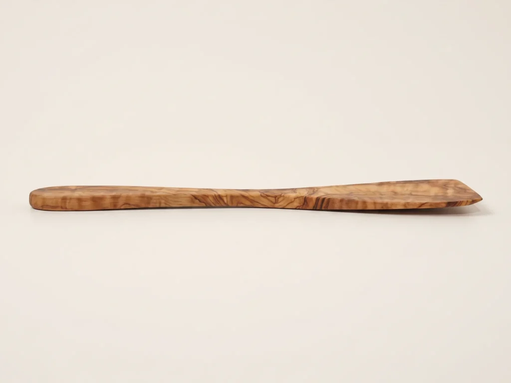 Vue de profil rasant montrant l'épaisseur et la finesse de la spatule plate en bois d'olivier