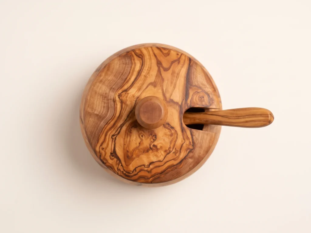 Overhead view of the olive wood sugar canister showing the round lid, the turned knob and the spoon