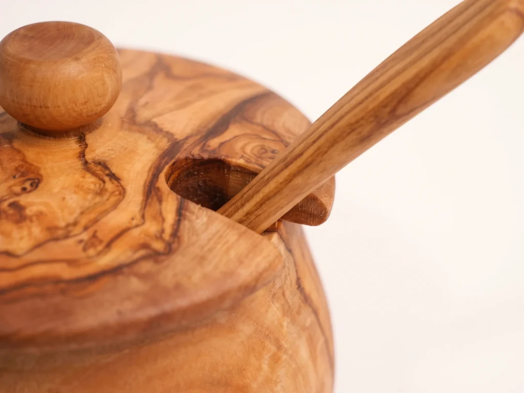 Macro detail of the lid notch and the matching olive wood spoon passing through it