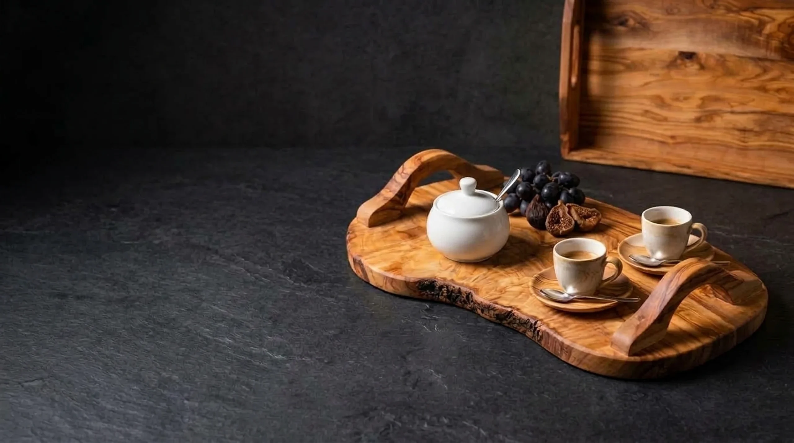 Handcrafted olive wood natural serving tray with raised bridge handles and espresso service on dark charcoal slate