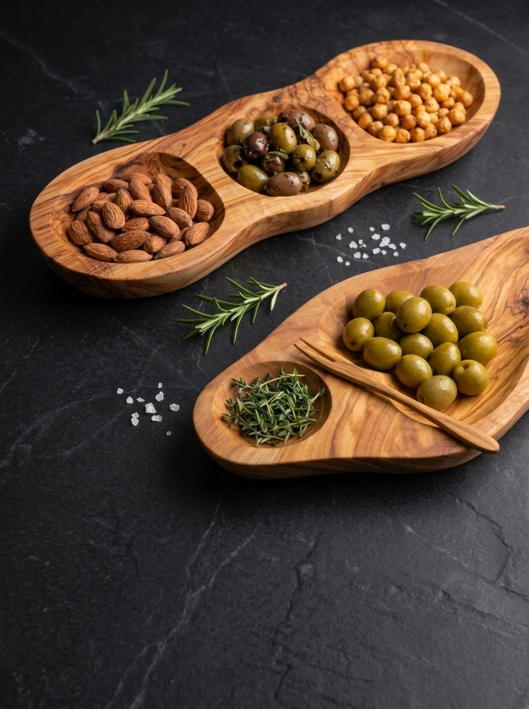 Sculpted olive wood appetizer dish with roasted almonds and olives on dark slate
