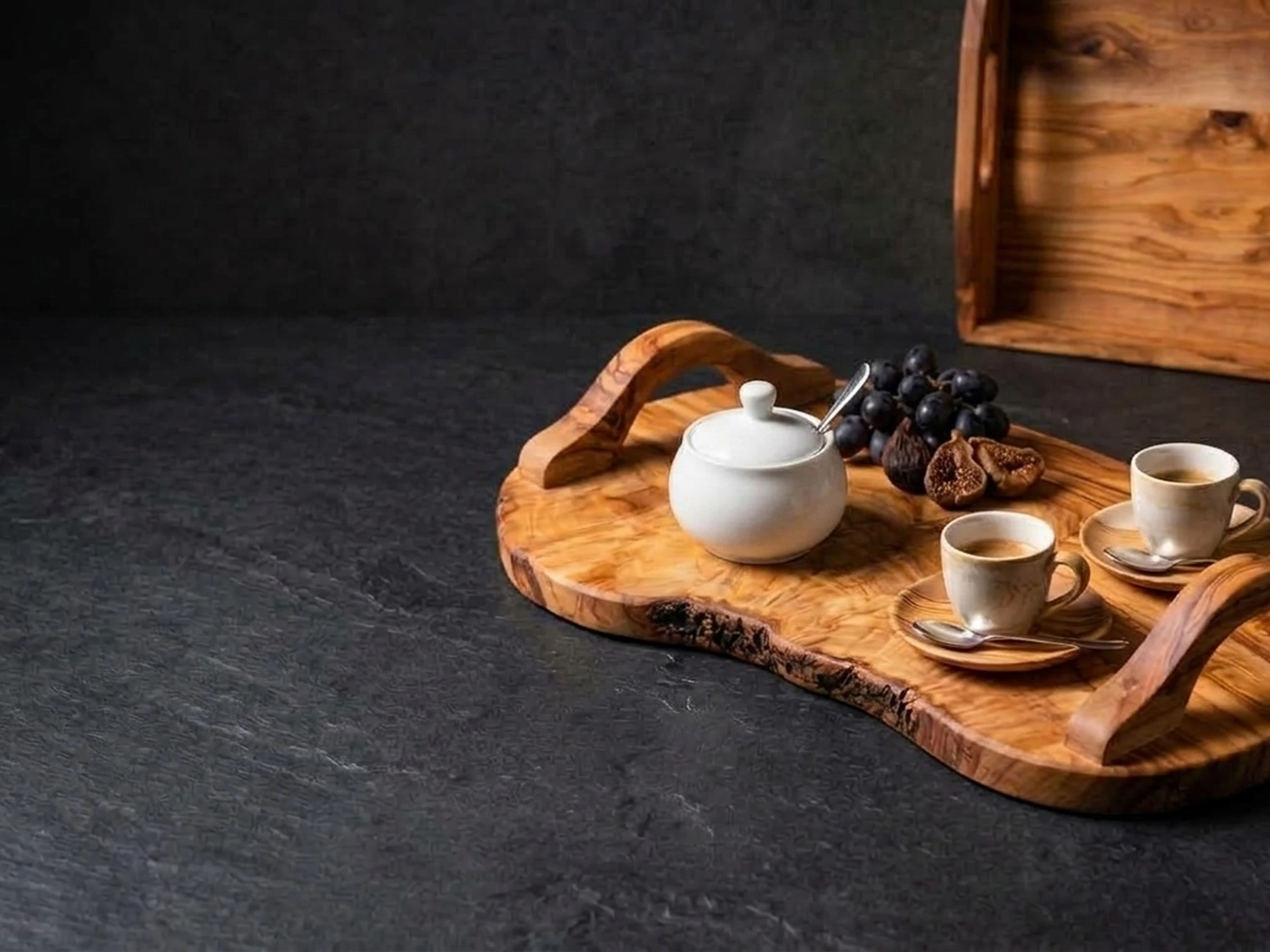 Handcrafted olive wood serving tray with natural edge on dark slate